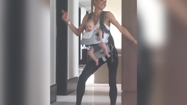 Анна Курникова танцует с малышом, сидящем в рюкзаке-кенгуру